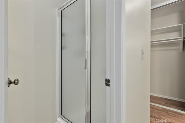 bathroom with baseboards, a shower stall, and wood finished floors