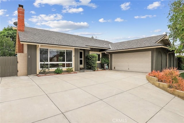 single story home featuring concrete driveway, a chimney, an attached garage, and a shingled roof
