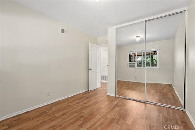 unfurnished bedroom with visible vents, baseboards, wood finished floors, and a closet