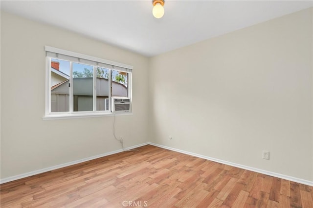 unfurnished room with baseboards, cooling unit, and light wood-style flooring