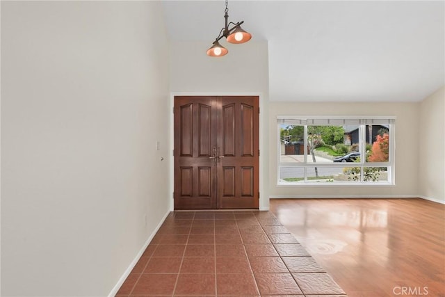 foyer featuring baseboards and vaulted ceiling