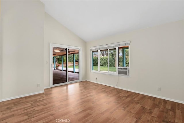 unfurnished room with baseboards, high vaulted ceiling, wood finished floors, and cooling unit