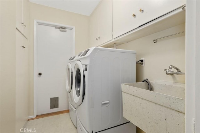 laundry room featuring cabinet space, light tile patterned floors, a sink, and washer and dryer