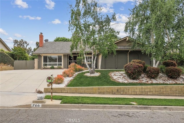 single story home with a chimney, fence, a front lawn, concrete driveway, and stucco siding