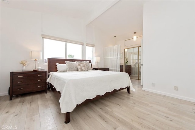 bedroom with ensuite bath, light wood-style floors, baseboards, and high vaulted ceiling