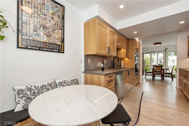 kitchen featuring a sink, stainless steel appliances, light wood-type flooring, decorative backsplash, and recessed lighting