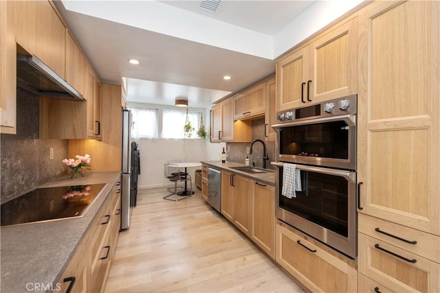 kitchen featuring light wood-style floors, stainless steel appliances, light brown cabinetry, and a sink