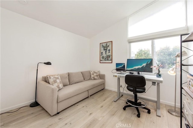 office featuring baseboards, light wood-style flooring, and vaulted ceiling