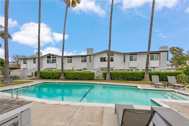 community pool with fence and a patio