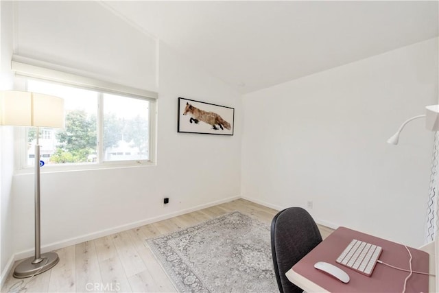 office space featuring light wood-type flooring, vaulted ceiling, and baseboards