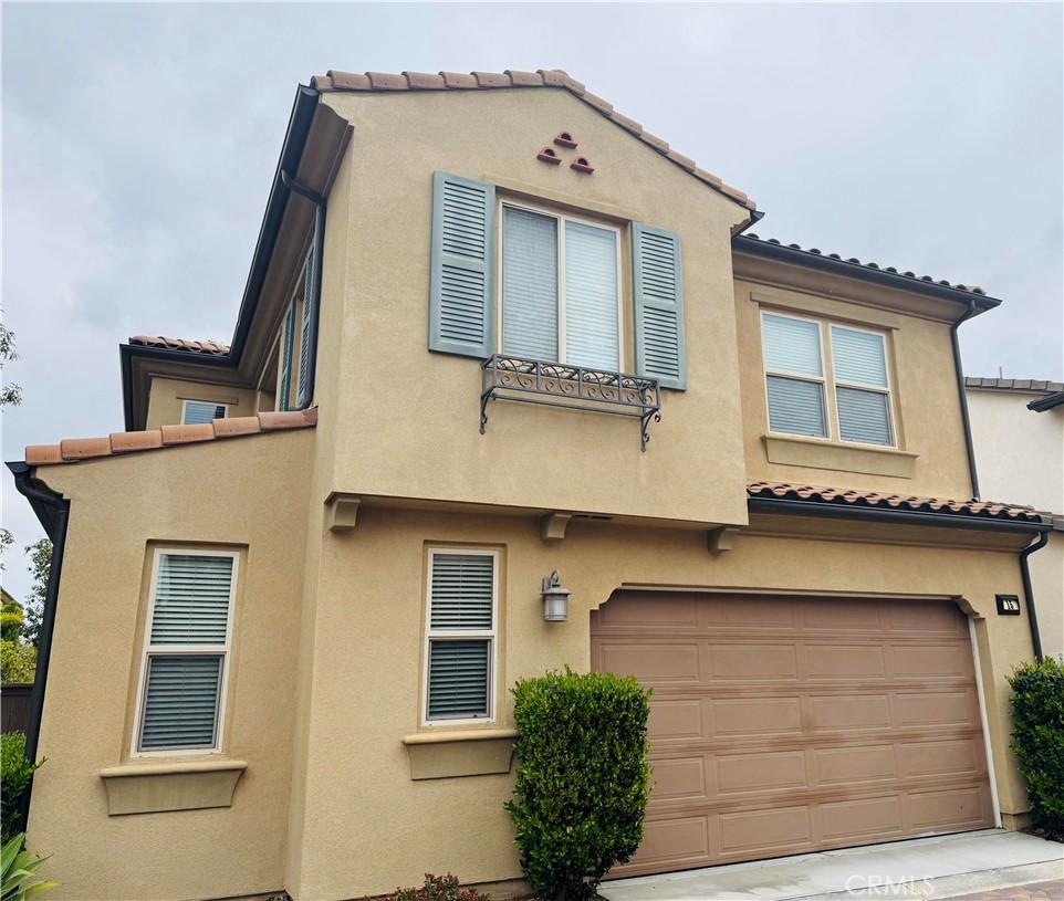 view of front of property featuring an attached garage, stucco siding, and a tiled roof