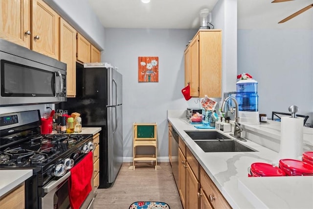 kitchen featuring light countertops, a sink, light wood-style flooring, and stainless steel appliances