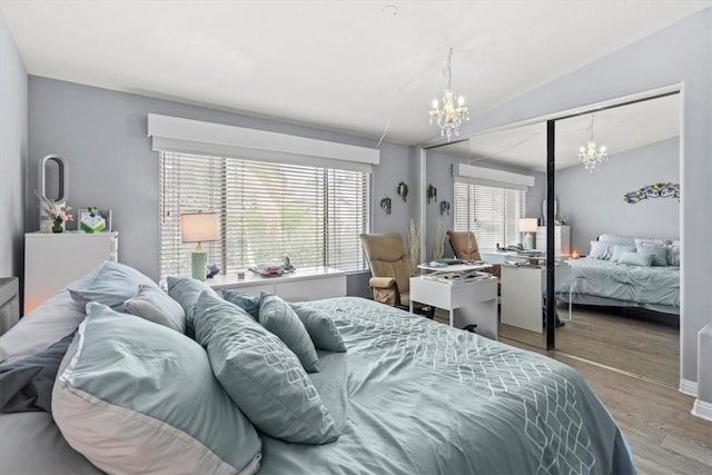 bedroom featuring a chandelier, wood finished floors, and vaulted ceiling