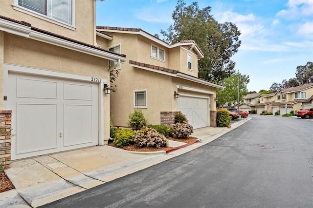 view of side of property featuring a garage, a residential view, and stucco siding