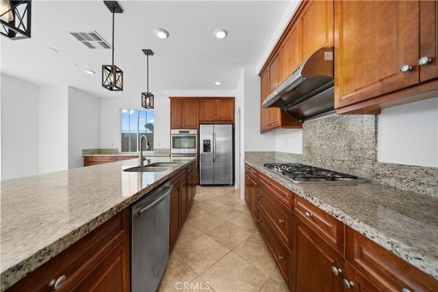 kitchen featuring stainless steel appliances, a sink, under cabinet range hood, decorative backsplash, and light stone counters