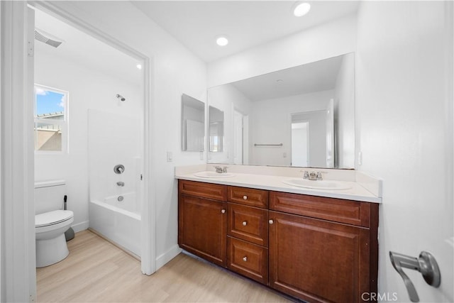 full bathroom featuring wood finished floors, double vanity, toilet, and shower / bathtub combination