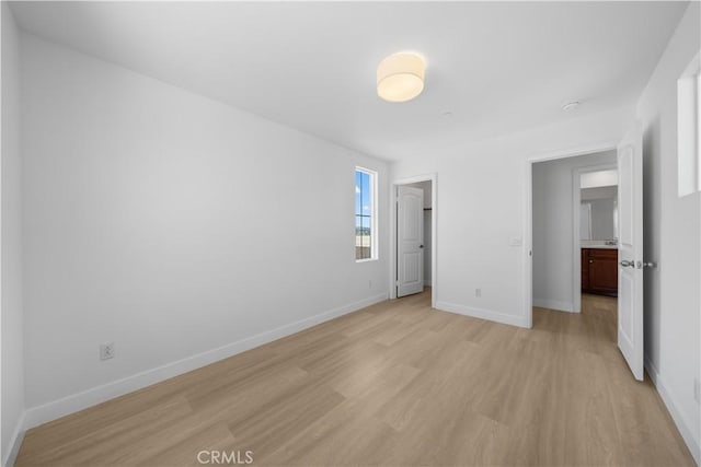unfurnished bedroom with light wood-style flooring and baseboards