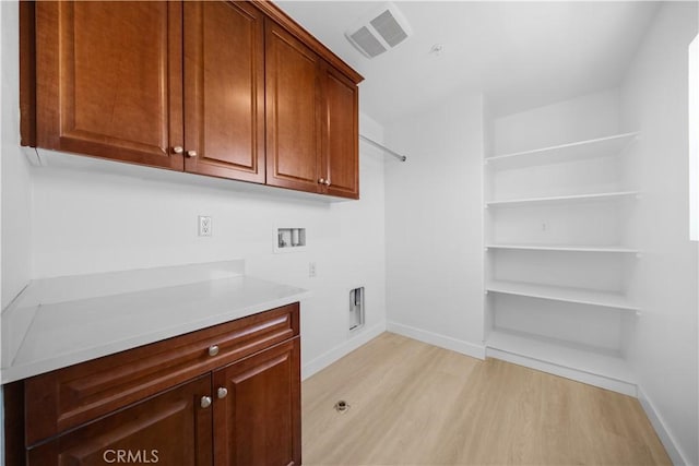 laundry room featuring cabinet space, light wood-style floors, hookup for a washing machine, and baseboards