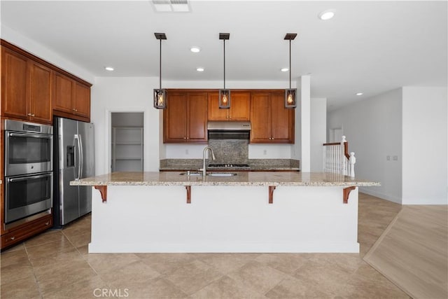 kitchen featuring stainless steel appliances, a sink, a breakfast bar, recessed lighting, and light stone counters