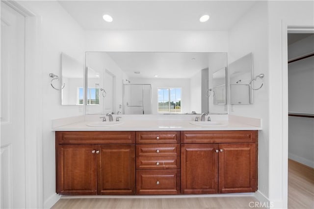 full bath with double vanity, wood finished floors, and baseboards