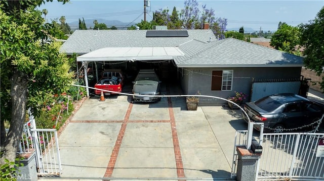 12036 Jouett St, Sylmar, CA 91342 - view of front facade featuring a shingled roof, roof mounted solar panels, stucco siding, a carport, and driveway