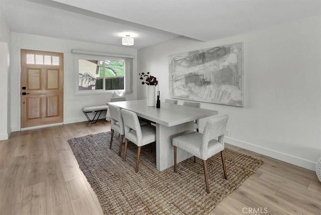 dining space with baseboards and light wood finished floors