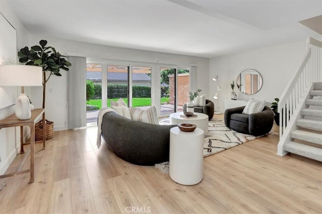 living area with light wood-type flooring and stairway