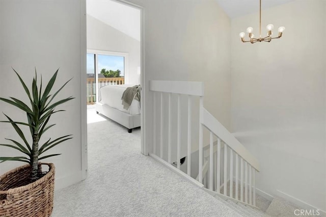 hallway with an inviting chandelier, carpet, vaulted ceiling, and an upstairs landing