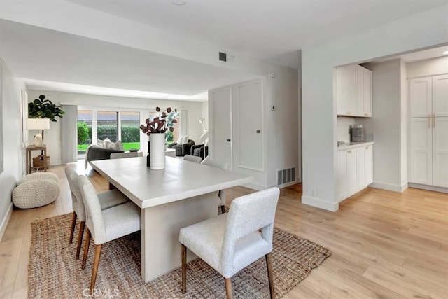 dining space featuring light wood-style floors, baseboards, and visible vents