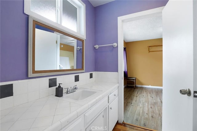 bathroom featuring vanity, a textured ceiling, wood finished floors, and a spacious closet