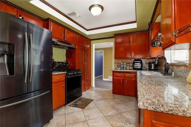 kitchen with black gas range oven, stainless steel fridge, a sink, under cabinet range hood, and visible vents