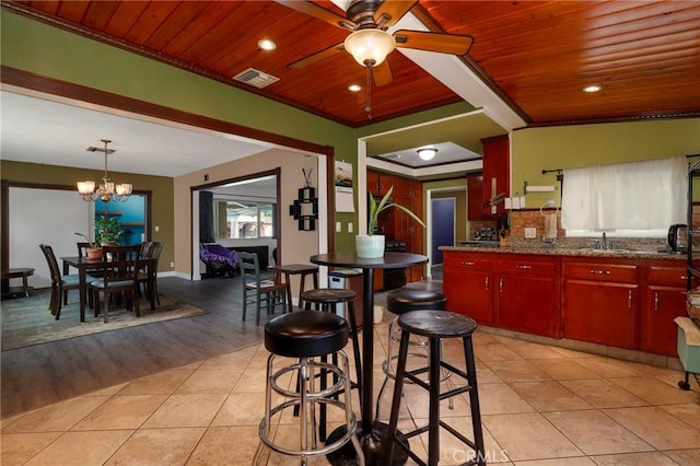 kitchen featuring a sink, ceiling fan with notable chandelier, wooden ceiling, light tile patterned floors, and visible vents