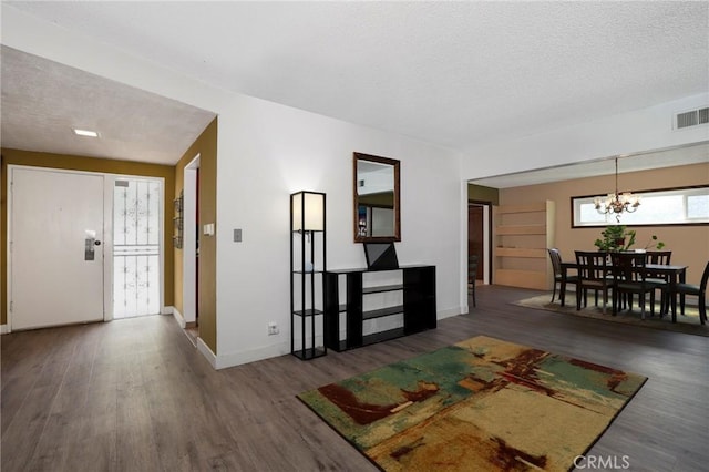 foyer featuring baseboards, a notable chandelier, visible vents, and wood finished floors