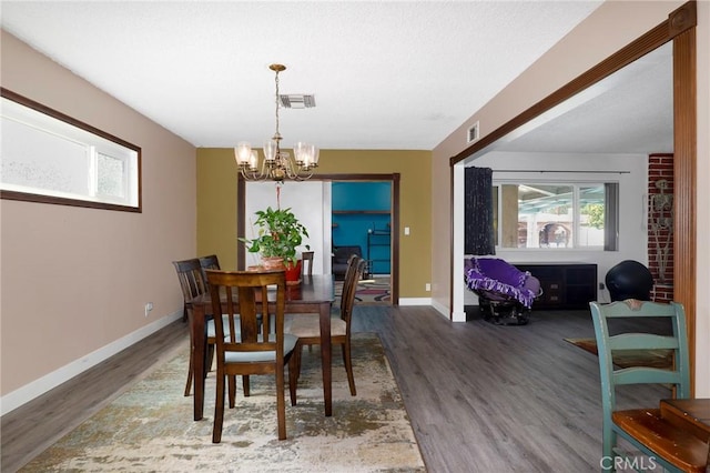 dining space with baseboards, wood finished floors, a notable chandelier, and visible vents