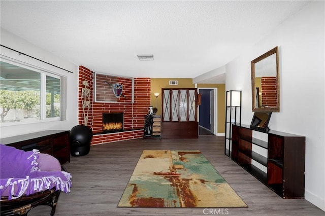 living area with baseboards, visible vents, wood finished floors, and a fireplace