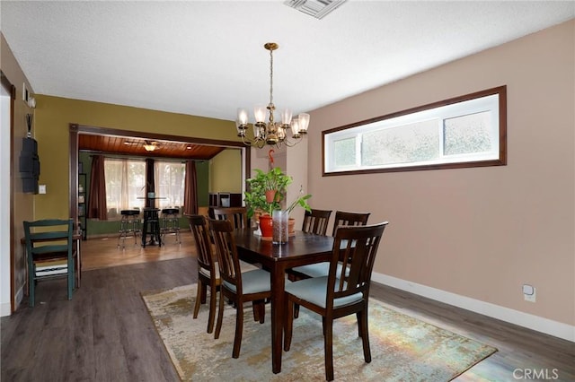 dining room with an inviting chandelier, baseboards, wood finished floors, and visible vents