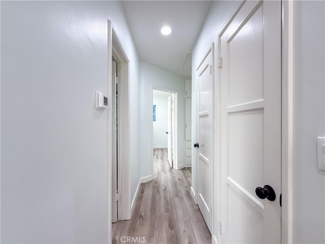 hallway with light wood-style floors, baseboards, and recessed lighting
