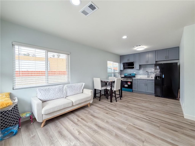living room featuring recessed lighting, baseboards, visible vents, and light wood-style flooring