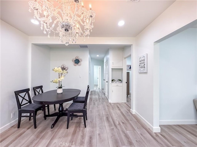 dining space with light wood-style floors, baseboards, a chandelier, and visible vents