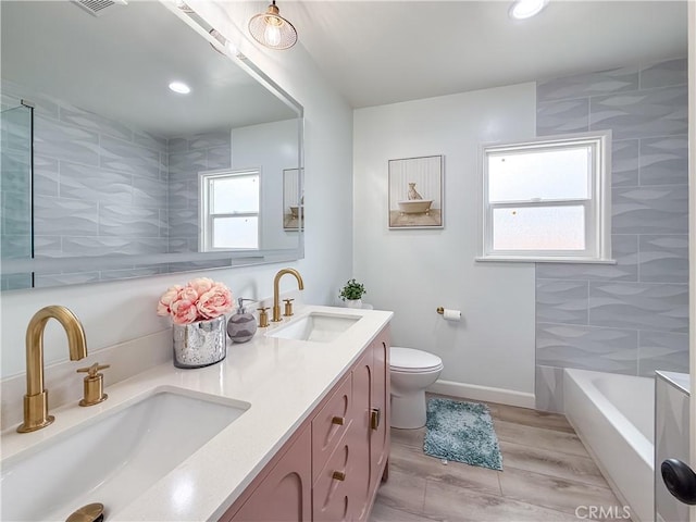 bathroom featuring double vanity, toilet, a sink, and wood finished floors