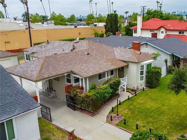 exterior space featuring a chimney, roof with shingles, a lawn, a residential view, and stucco siding