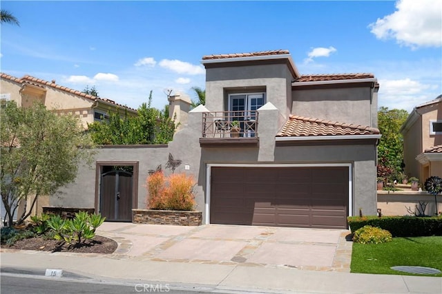 mediterranean / spanish home featuring a balcony, stucco siding, driveway, a tiled roof, and a garage