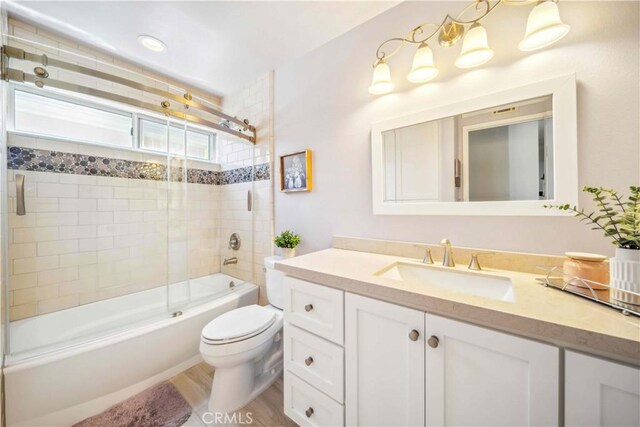 bathroom featuring toilet, vanity, enclosed tub / shower combo, and wood finished floors