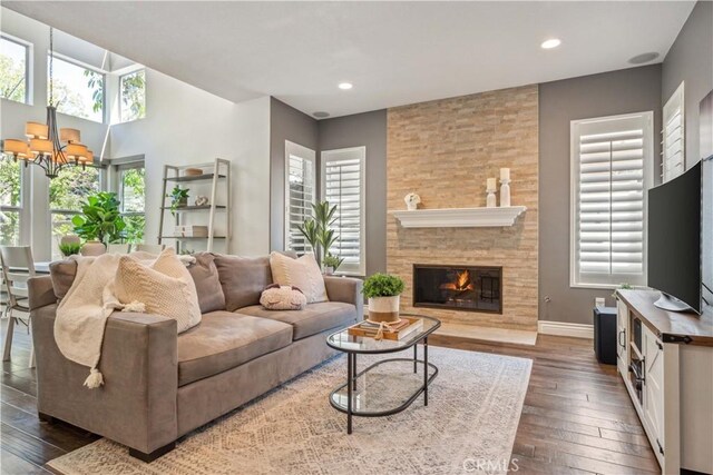 living area with dark wood-type flooring, a chandelier, baseboards, recessed lighting, and a fireplace
