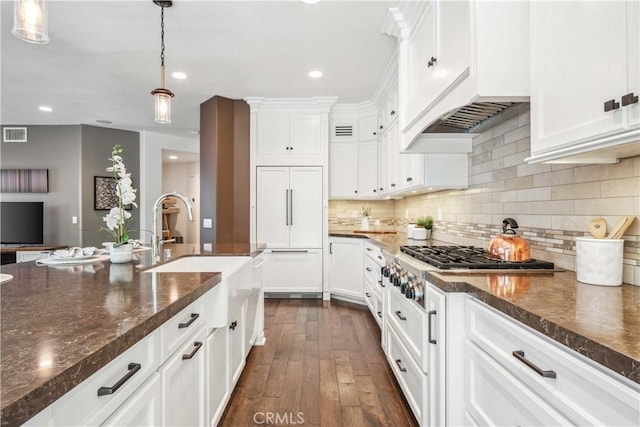 kitchen featuring paneled refrigerator, a sink, white cabinetry, and recessed lighting