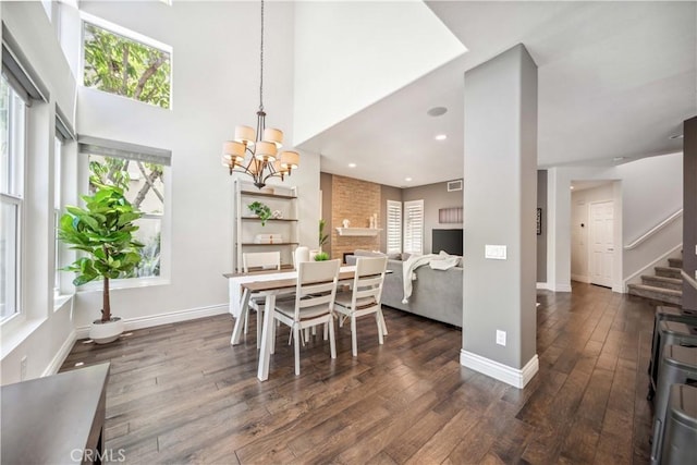 dining room featuring dark wood-style floors, stairway, a chandelier, baseboards, and a towering ceiling