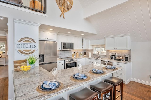 27550 N Bay Rd, Lake Arrowhead, CA 92352 - kitchen with appliances with stainless steel finishes, a sink, a breakfast bar, wood finished floors, and white cabinets
