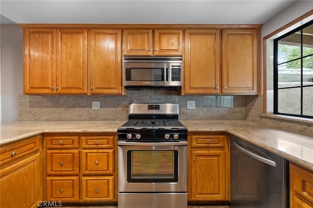 kitchen with brown cabinets, stainless steel appliances, and decorative backsplash