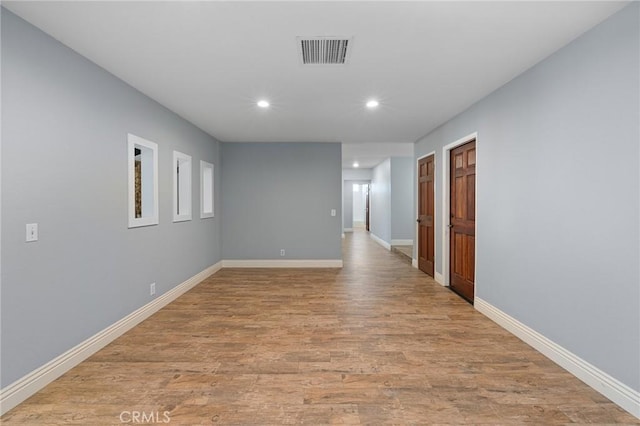 hall featuring visible vents, recessed lighting, baseboards, and light wood finished floors