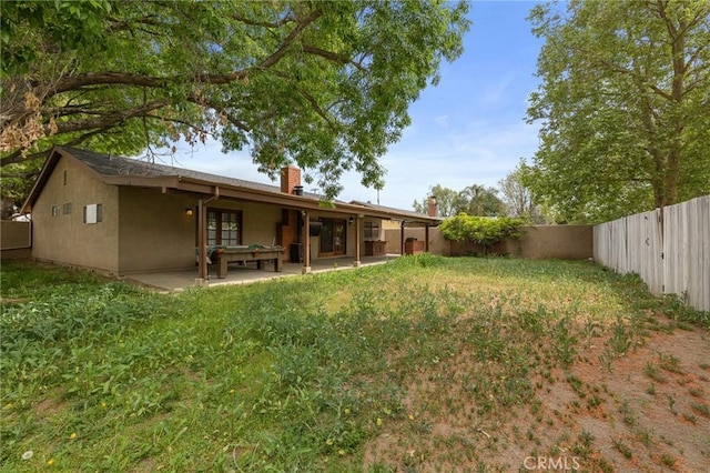 back of house featuring a fenced backyard, a chimney, a patio area, and stucco siding